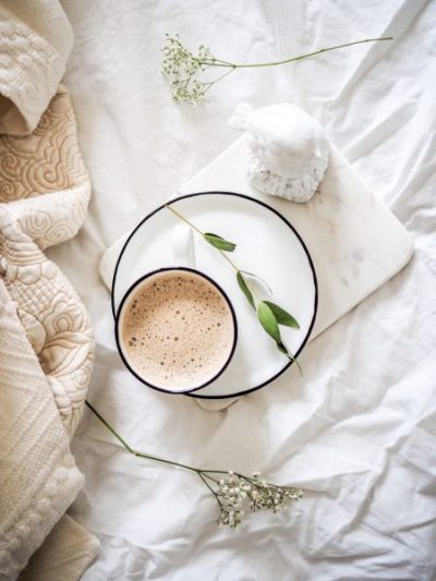 Flat lay of a fresh cup of coffee being served in bed