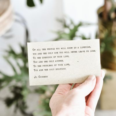 A hand holding a cue card with a few lines written by Jo Coudert